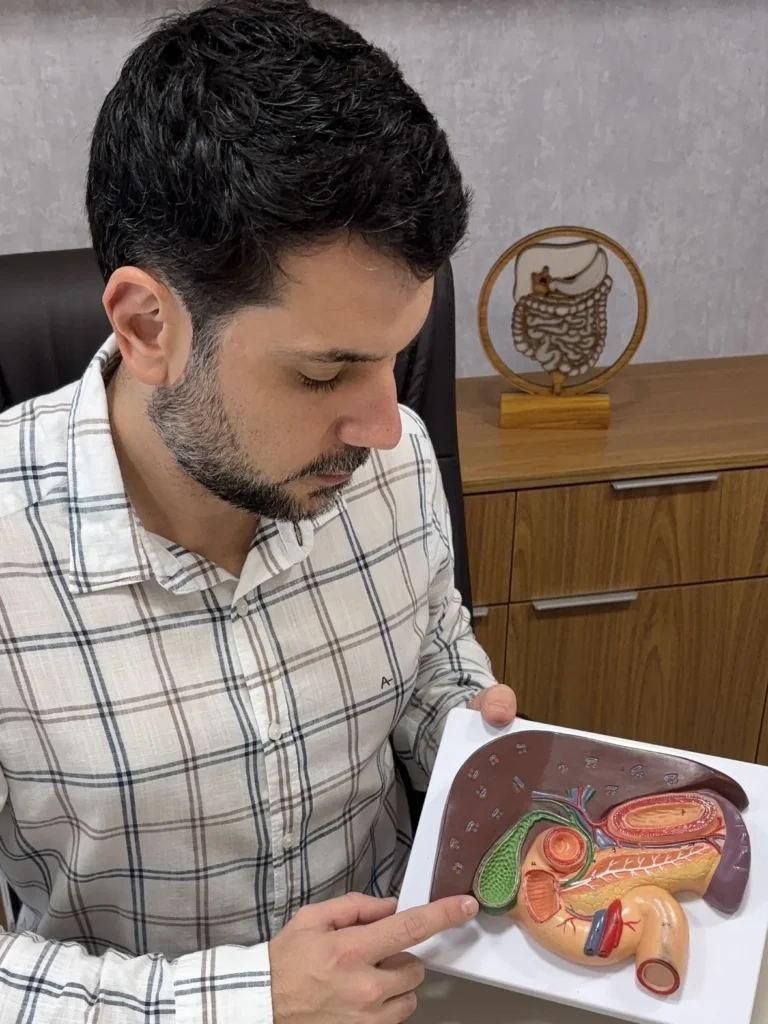 Dr. Gustavo Pinheiro Machado explicando a anatomia da via biliar em um modelo anatômico, no consultório
